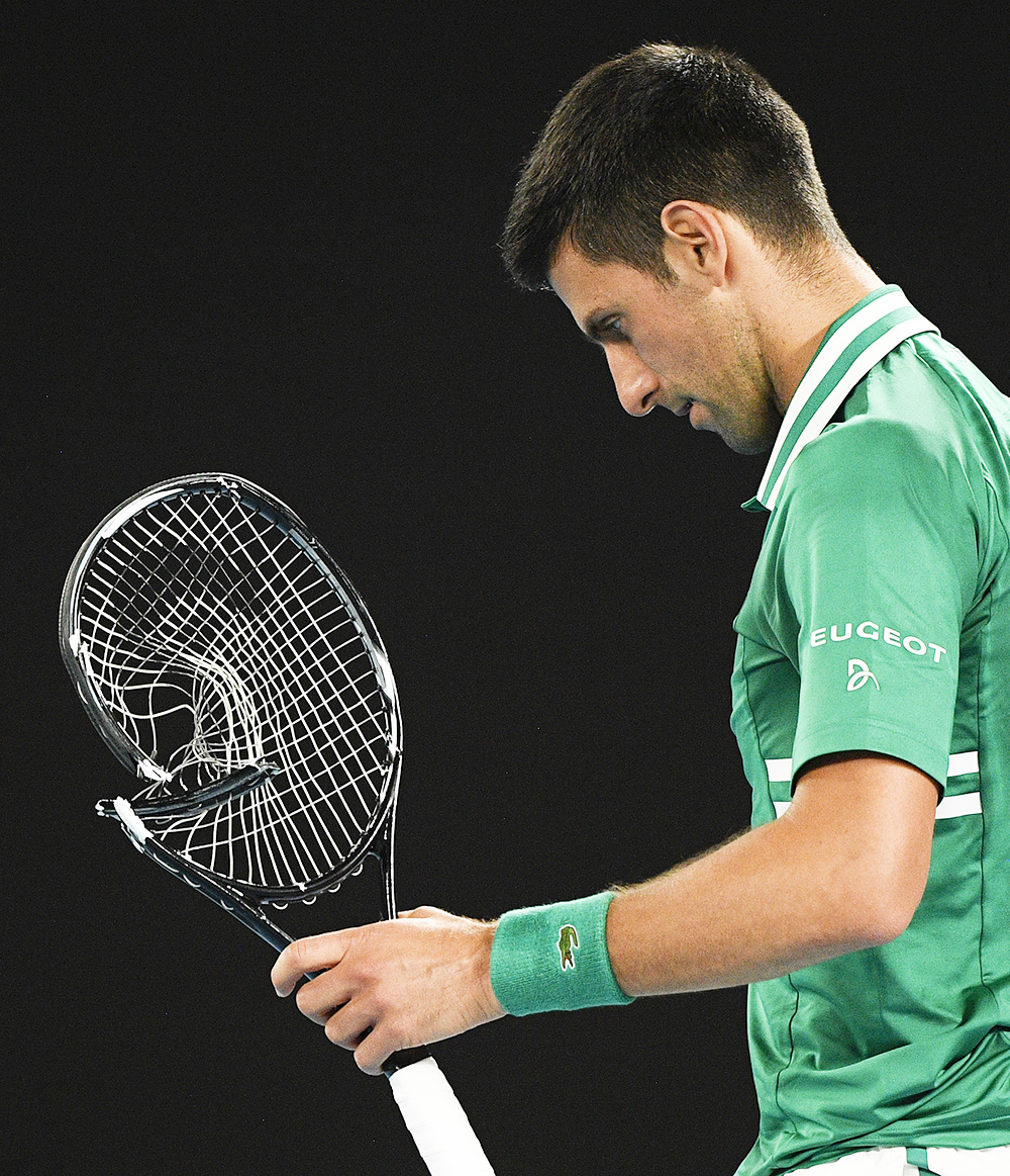 Serbia's Novak Djokovic walks to replace his smashed racket during his quarterfinal match against Germany's Alexander Zverev at the Australian Open tennis championship in Melbourne, Australia, Tuesday, Feb. 16, 2021.(AP Photo/Andy Brownbill)