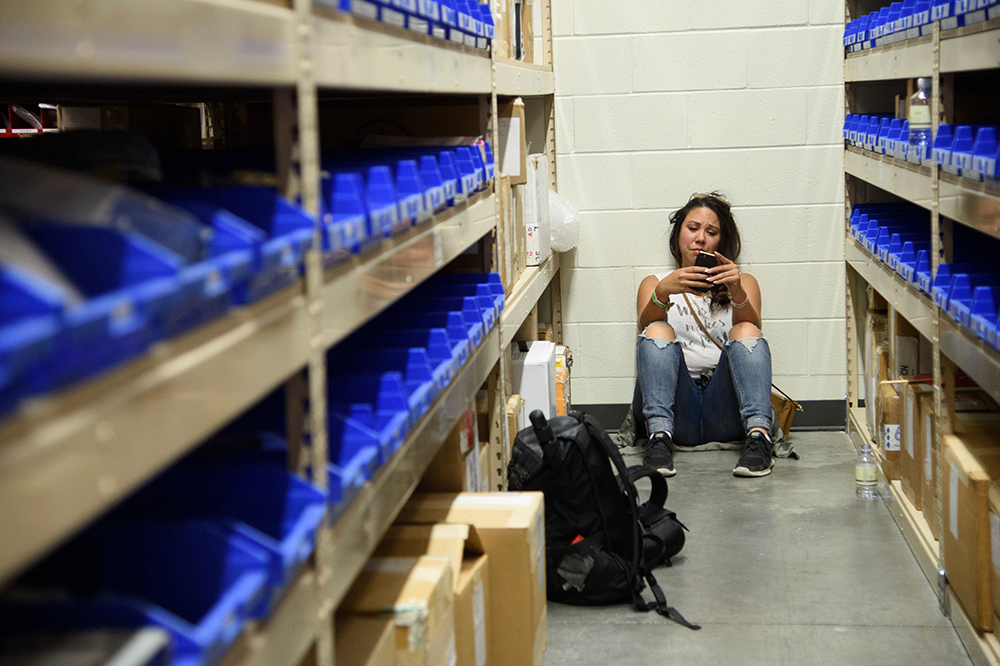 A young woman checks her phone while hiding inside the Sands Corporation plane hangar after a mass shooting in which dozens were killed at the Route 91 Harvest Festival, in Las Vegas
Shooting, Las Vegas, USA - 01 Oct 2017