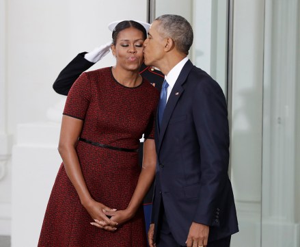 President Barack Obama kisses first lady Michelle Obama as they await for the arrival of President-elect Donald Trump and his wife Melania, Friday, Jan. 20, 2017, at the White House in Washington. (AP Photo/Evan Vucci)