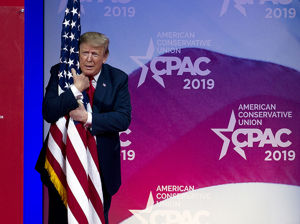 President Donald Trump hugs the American flag as he arrives to speak at Conservative Political Action Conference, CPAC 2019, in Oxon Hill, Md., Saturday, March 2, 2019. (AP Photo/Jose Luis Magana)