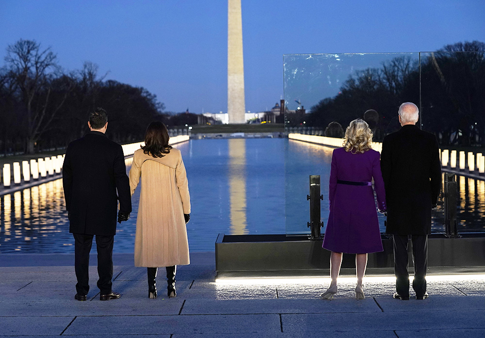 With the Washington Monument in the background, President-elect Joe Biden stands with his wife Jill Biden and Vice President-elect Kamala Harris stands with her husband Doug Emhoff as they look at lights placed around the Lincoln Memorial Reflecting Pool during a COVID-19 memorial Tuesday, Jan. 19, 2021, in Washington. (AP Photo/Evan Vucci)