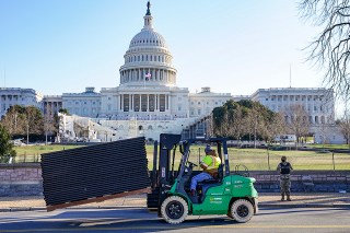 DC National Guard stands outside a mostly quiet Capitol, Thursday morning, Jan. 7, 2021 in Washington, as workers place security fencing in place. The House and Senate certified the Democrat's electoral college win early Thursday after a violent throng of pro-Trump rioters spent hours Wednesday running rampant through the Capitol. A woman was fatally shot, windows were bashed and the mob forced shaken lawmakers and aides to flee the building, shielded by Capitol Police. (AP Photo/John Minchillo)