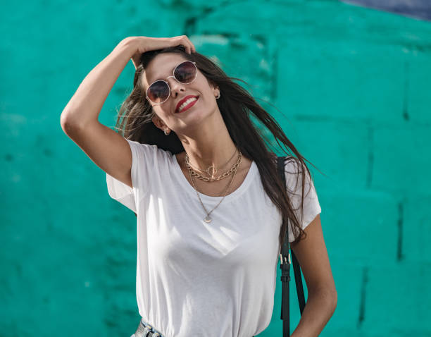 Cheerful young woman in white t-shirt and golden necklace.