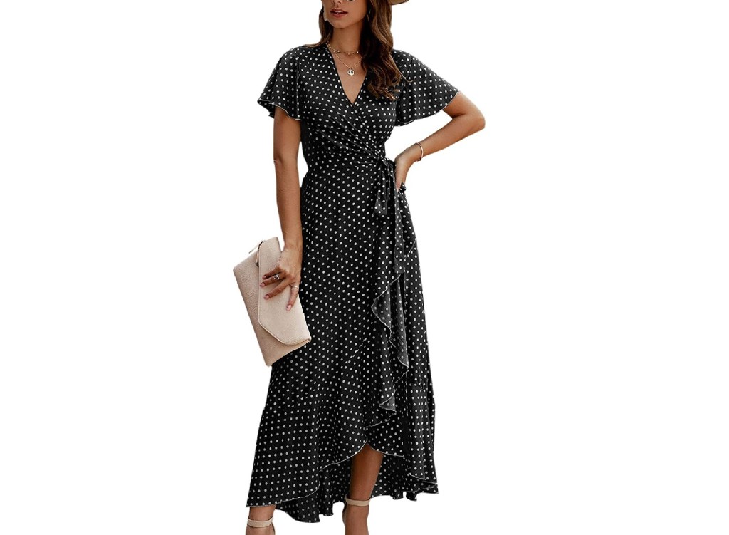A model wearing a black wrap dress with polkadots.