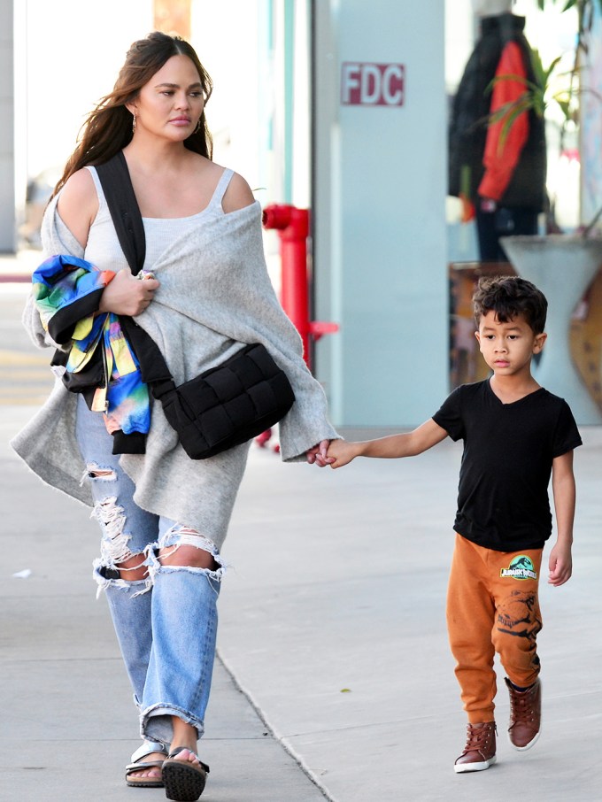 Chrissy Teigen holds her son’s hand