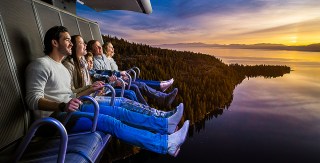 Aerial drone view perfect redwoods and sequoia and Jeffrey pines and Western Yellow Pines running along the shoreline of majestic Lake Tahoe at sunrise looking down on trees and waters edge with Sierra Nevada Mountains in background