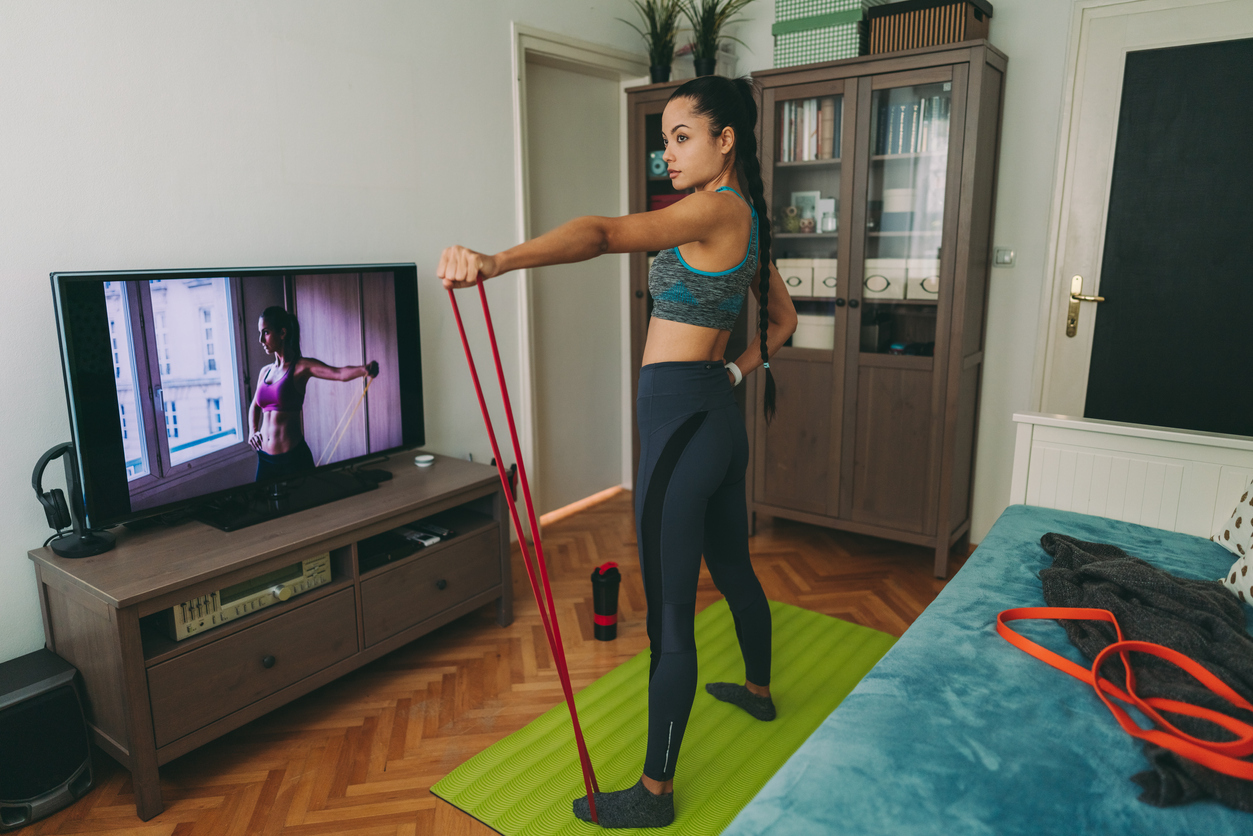 A woman works out from home with a pair of resistance bands