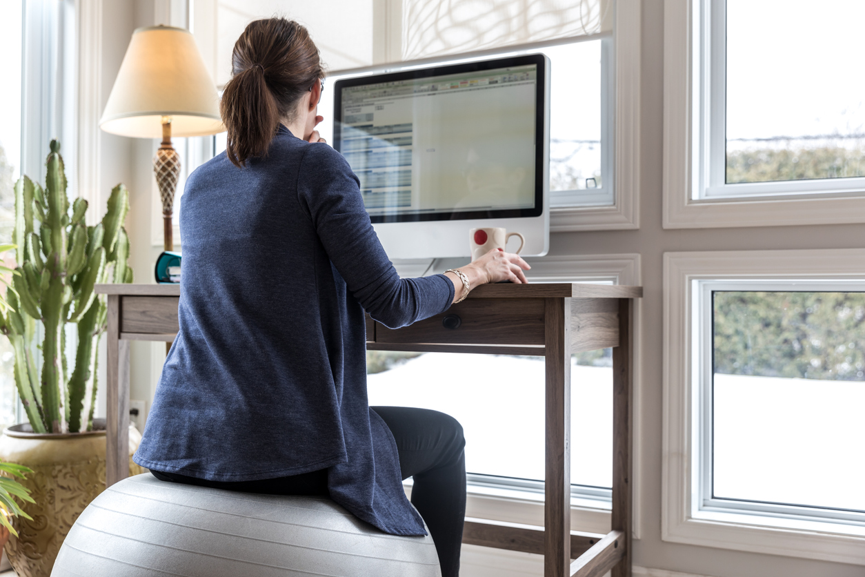 A woman works from home sitting on an exercise ball