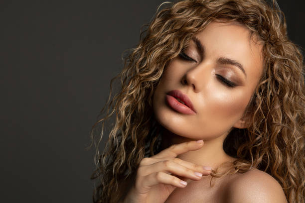 Fashion studio portrait of adorable blonde woman with lush hair and naked shoulders. Empty space