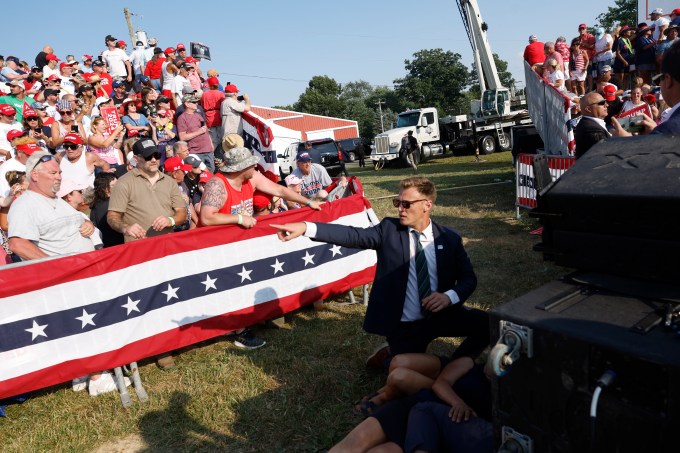 Secret Service agent points towards something in crowd