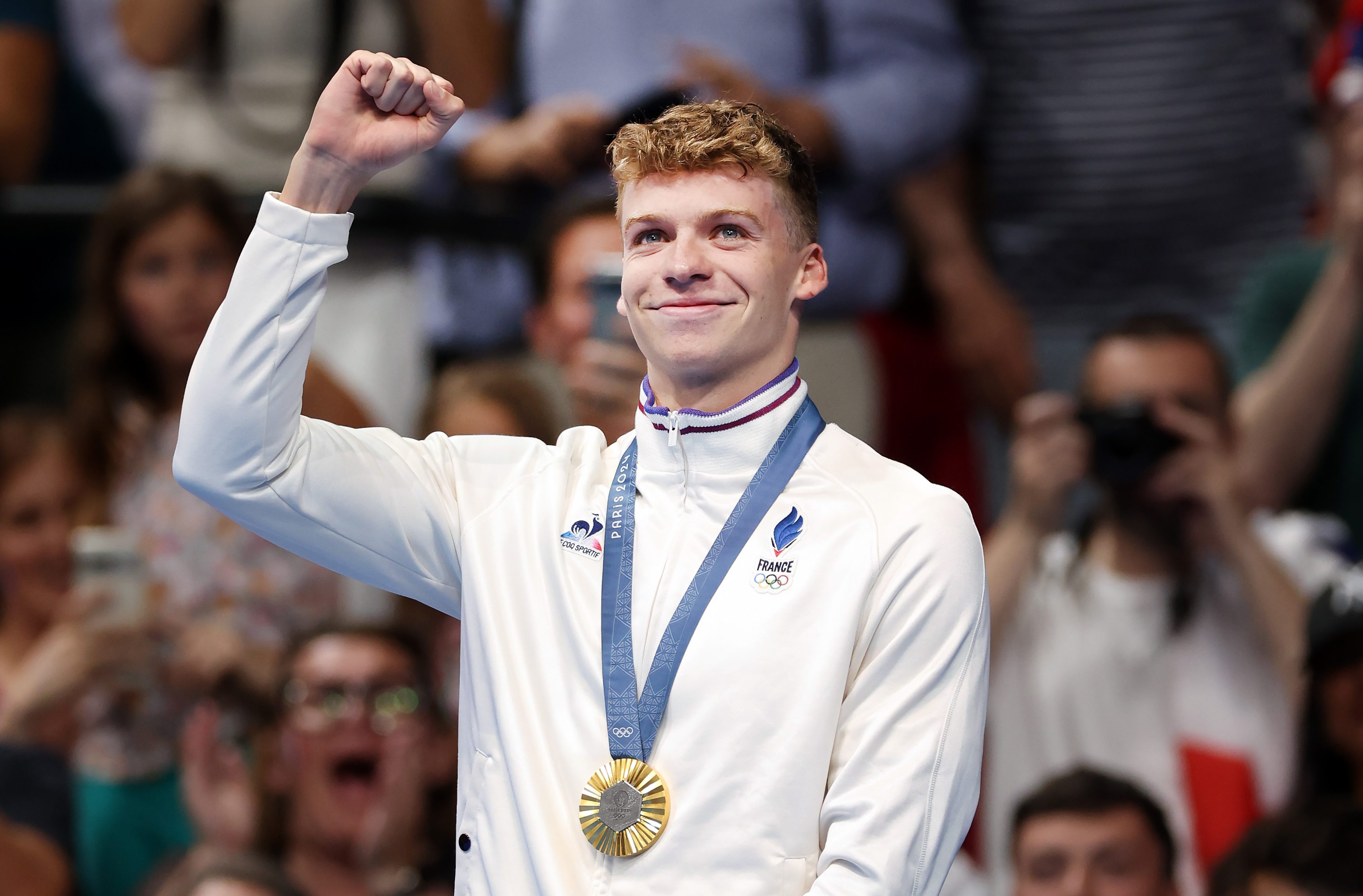 Leon Marchand of Team France celebrates on the podium after victory in the Men's 400m IM final on day two of the Olympic Games Paris 2024 at Paris La Defense Arena on July 28, 2024 in Nanterre, France. (Photo by Ian MacNicol/Getty Images)