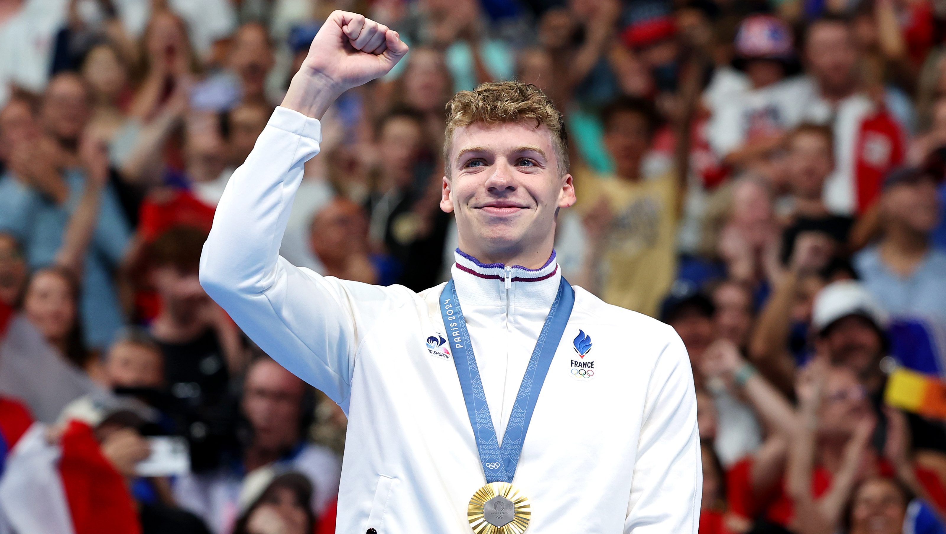 NANTERRE, FRANCE - JULY 28: Gold Medalist Leon Marchand of Team France celebrates on the podium during the Swimming medal ceremony after the Men’s 400m Individual Medley Final on day two of the Olympic Games Paris 2024 at Paris La Defense Arena on July 28, 2024 in Nanterre, France. (Photo by Quinn Rooney/Getty Images)
