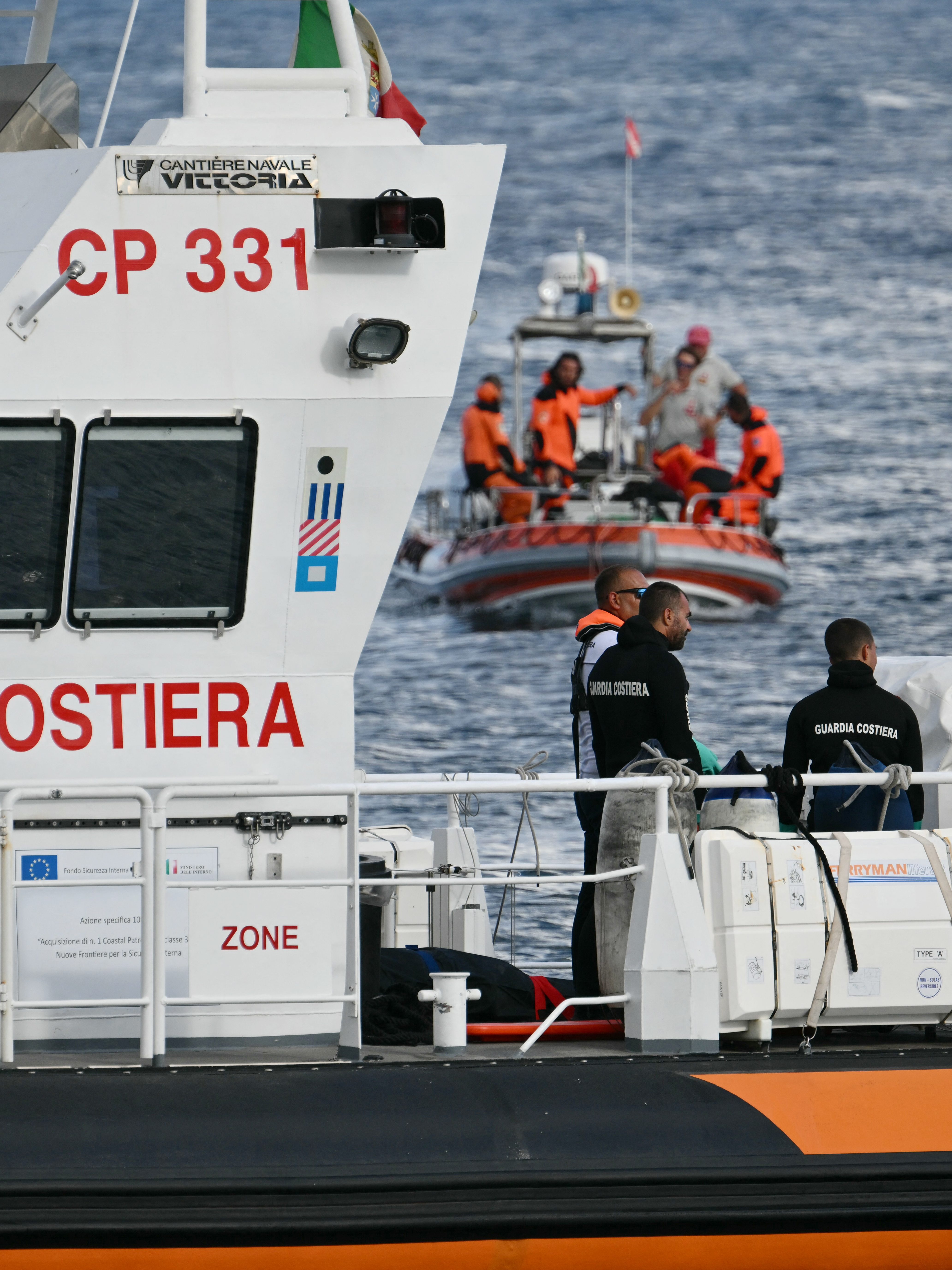 Italian Coast Guards carry a body on a rescue boat in Porticello harbor near Palermo, with a third body at the back of the boat on August 21, 2024, two days after the British-flagged luxury yacht Bayesian sank. Divers searching for six missing people following the sinking of a superyacht off Sicily in a storm have found four bodies, a source close to the search told AFP. The Bayesian, which had 22 people aboard including 10 crew, was anchored some 700 metres from port before dawn when it was struck by a waterspout. Among the six missing were UK tech entrepreneur Mike Lynch and his 18-year-old daughter Hannah, and Jonathan Bloomer, the chair of Morgan Stanley International, and his wife Judy. (Photo by Alberto PIZZOLI / AFP) (Photo by ALBERTO PIZZOLI/AFP via Getty Images)