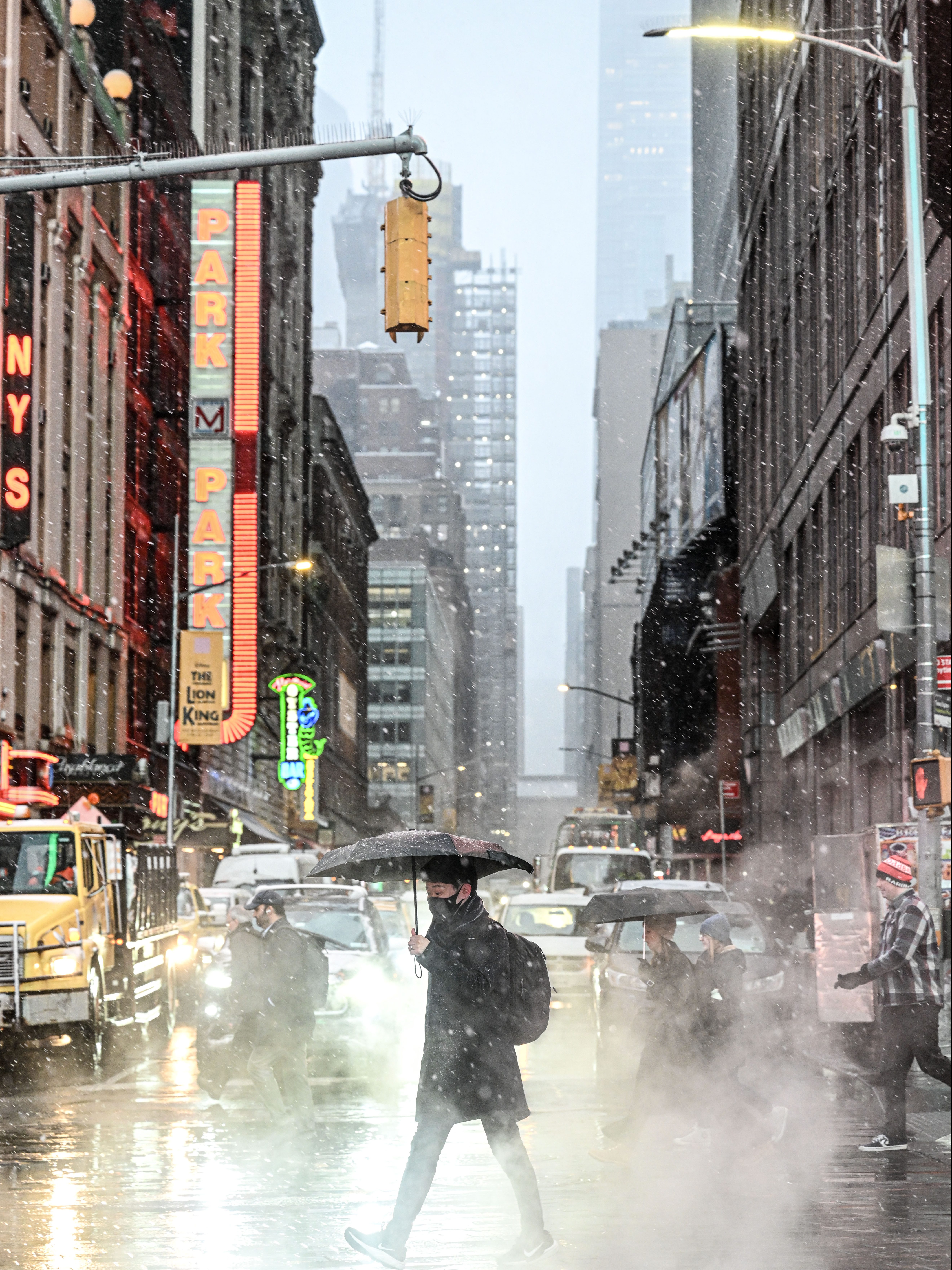 NEW YORK, UNITED STATES - FEBRUARY 13: A man crosses the road with an umbrella during a snowfall at Times Square in New York, United States on February 13, 2024. (Photo by Fatih Aktas/Anadolu via Getty Images)
