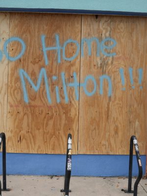 People walk past boarded up storefronts in Tampa ahead of Hurricane Milton's expected landfall in the middle of this week on October 8, 2024 in Florida. Hurricane Milton exploded in strength October 7 to become a potentially catastrophic Category 5 storm bound for Florida, threatening the US state with a second ferocious hurricane in as many weeks. (Photo by Bryan R. SMITH / AFP) (Photo by BRYAN R. SMITH/AFP via Getty Images)