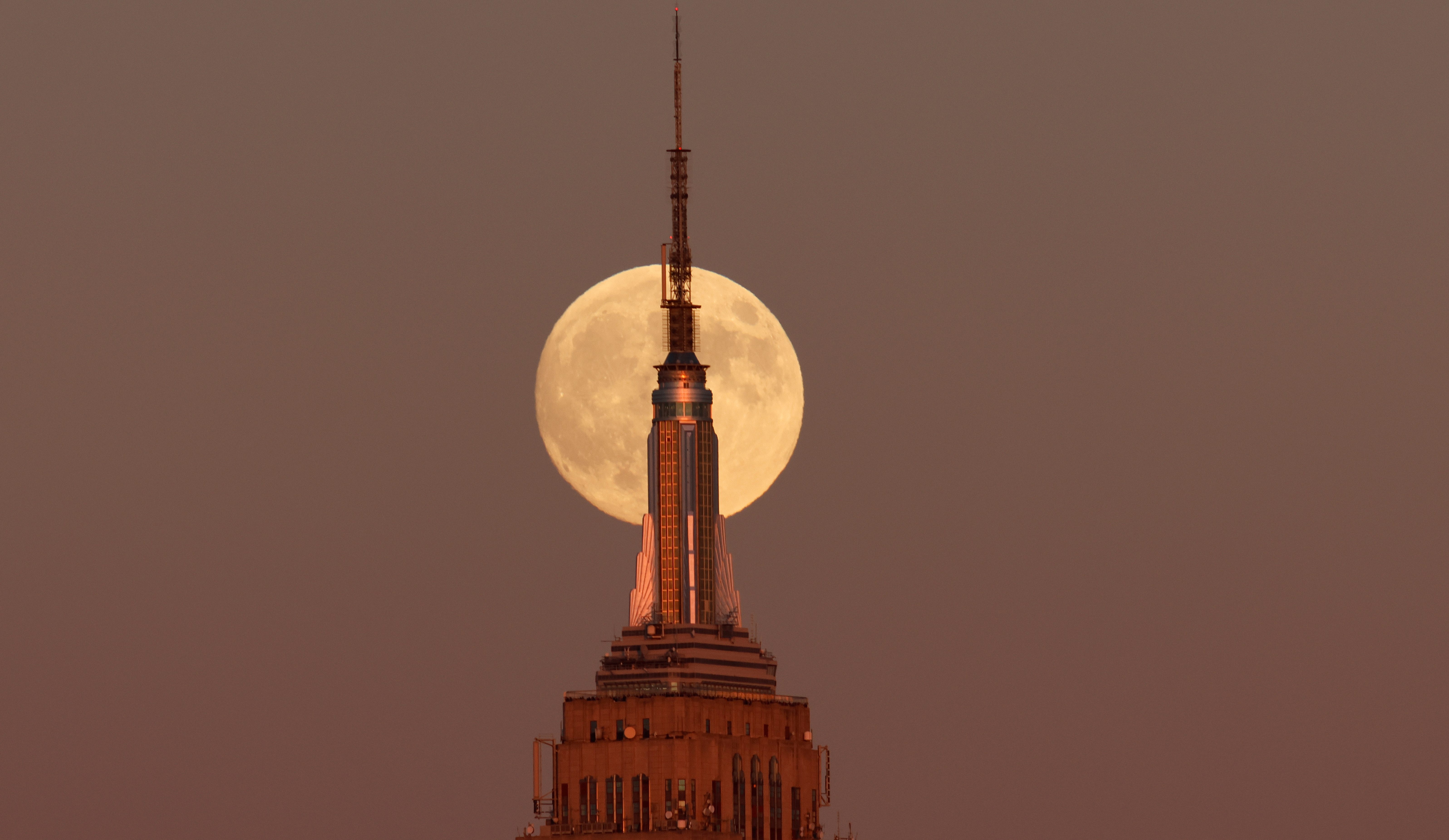 JERSEY CITY, NJ - OCTOBER 16: The Hunter's Supermoon rises behind the Empire State Building in New York City as the sun sets on October 16, 2024, as seen from Jersey City, New Jersey. (Photo by Gary Hershorn/Getty Images)