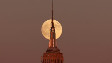 JERSEY CITY, NJ - OCTOBER 16: The Hunter's Supermoon rises behind the Empire State Building in New York City as the sun sets on October 16, 2024, as seen from Jersey City, New Jersey.  (Photo by Gary Hershorn/Getty Images)