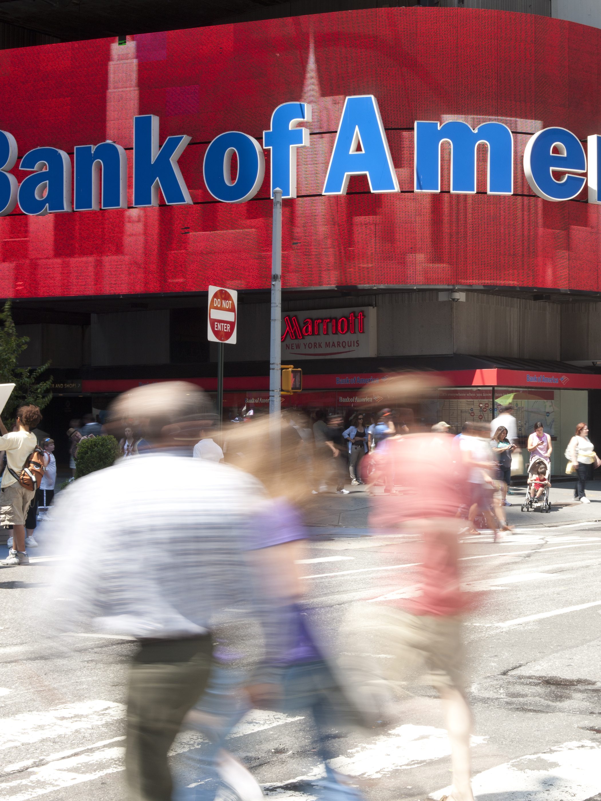 Manhattan, New York USA - July 9, 2011: People and tourist walking by the colorful electronic sign of Bank of America. The sign is one of many colorful signs in Times Square.