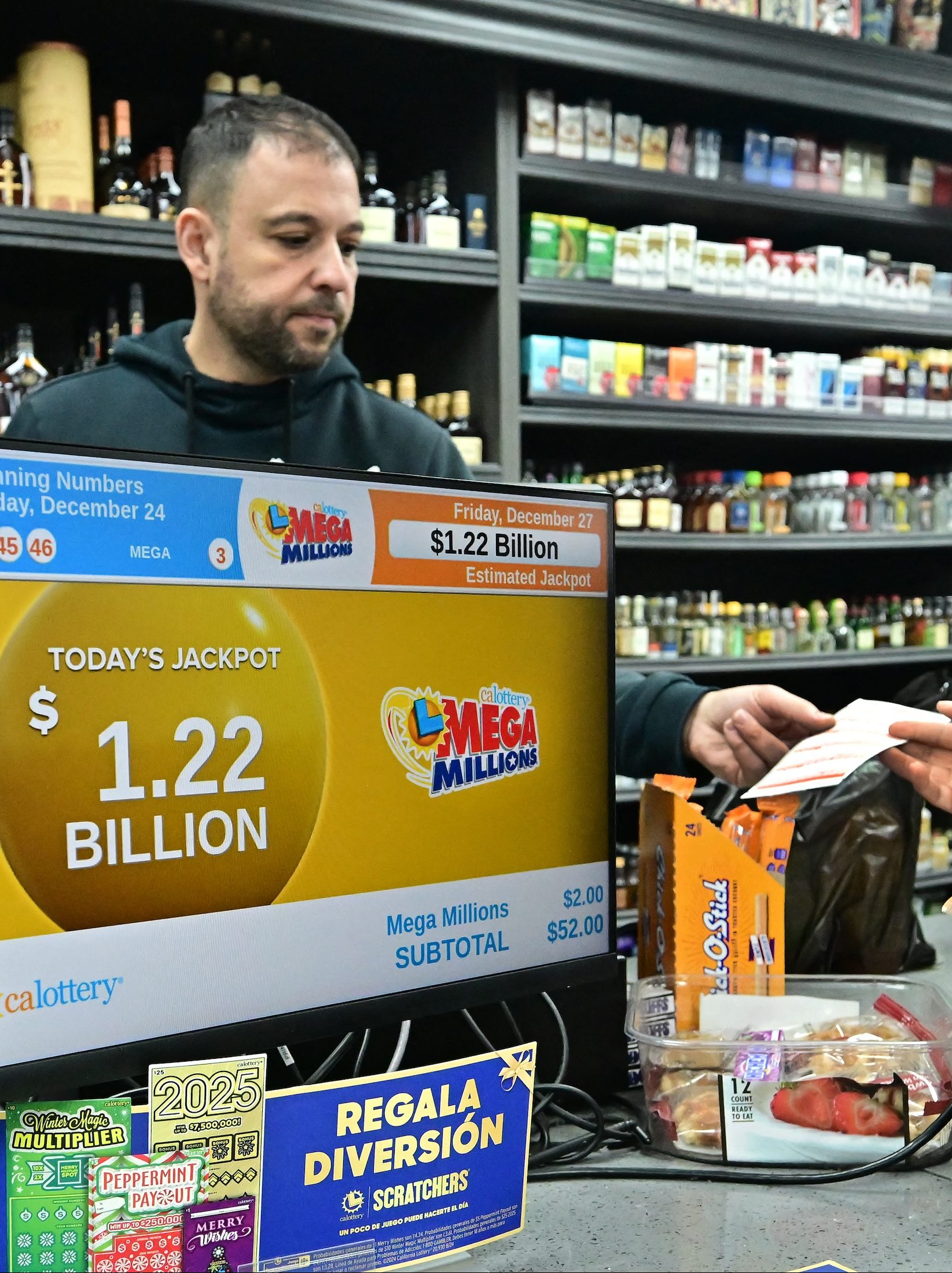 A person purchases their Mega Millions lottery ticket from a liquor store where winning tickets have been sold on December 27, 2024 in Hawthorne, California. The ninth-largest lottery jackpot in US history worth $1.15 billion will be drawn tonight in the Mega Millions drawing, after no tickets with all six numbers have been sold in 30 consecutive drawings. (Photo by Frederic J. BROWN / AFP)